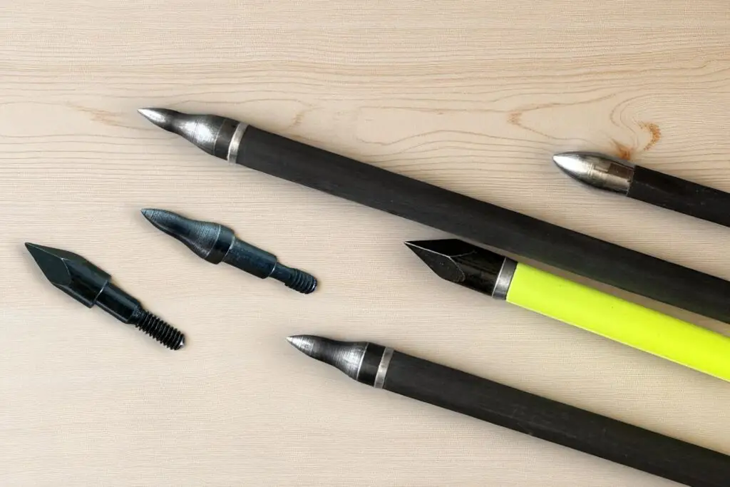 carbonpfeil pfeilspitzen unetrschiedlicher art vor einem holzhintergrund